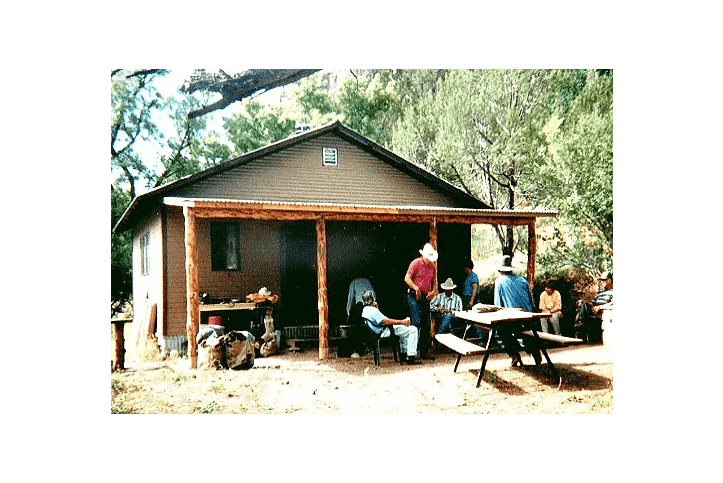 A group of people sitting at tables outside of a cabin.